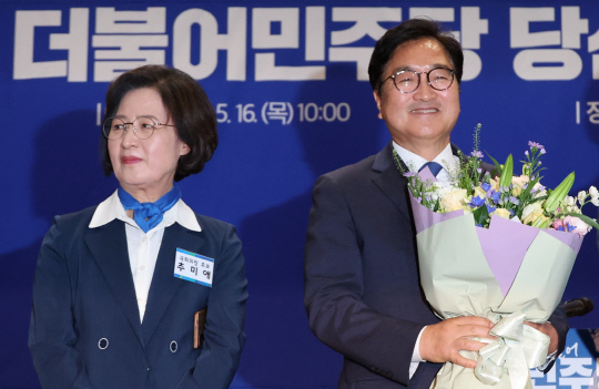 지난 5월16일 더불어민주당의 제22대 전반기 국회 의장 후보로 선출된 5선 우원식 의원이 국회 의원회관에서 열린 민주당 국회의원 당선인 총회에서 꽃다발을 받고 환하게 웃고 있다. 왼쪽은 국회의장 후보 경선 맞수였으나 고배를 마신 6선 추미애 당선인.<연합뉴스 사진>